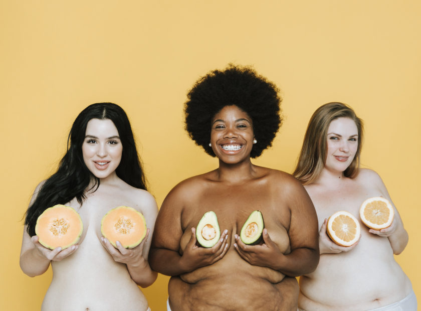 Diverse curvy nude women holding fruits over their breasts