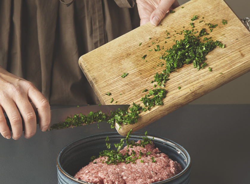 woman-hands-add-fresh-green-parsley-minced-meat-beautiful-ceramic-bowl-old-wooden-table